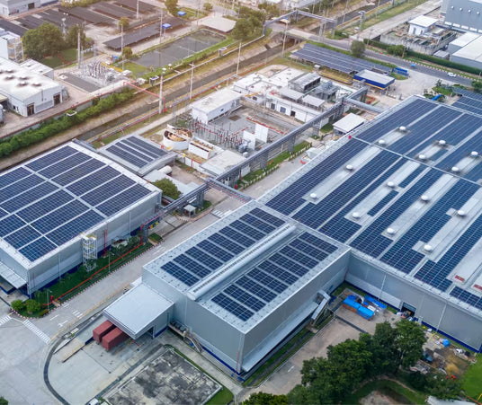 Aerial view of a large commercial facility with full rooftop solar panel installation for industrial energy production