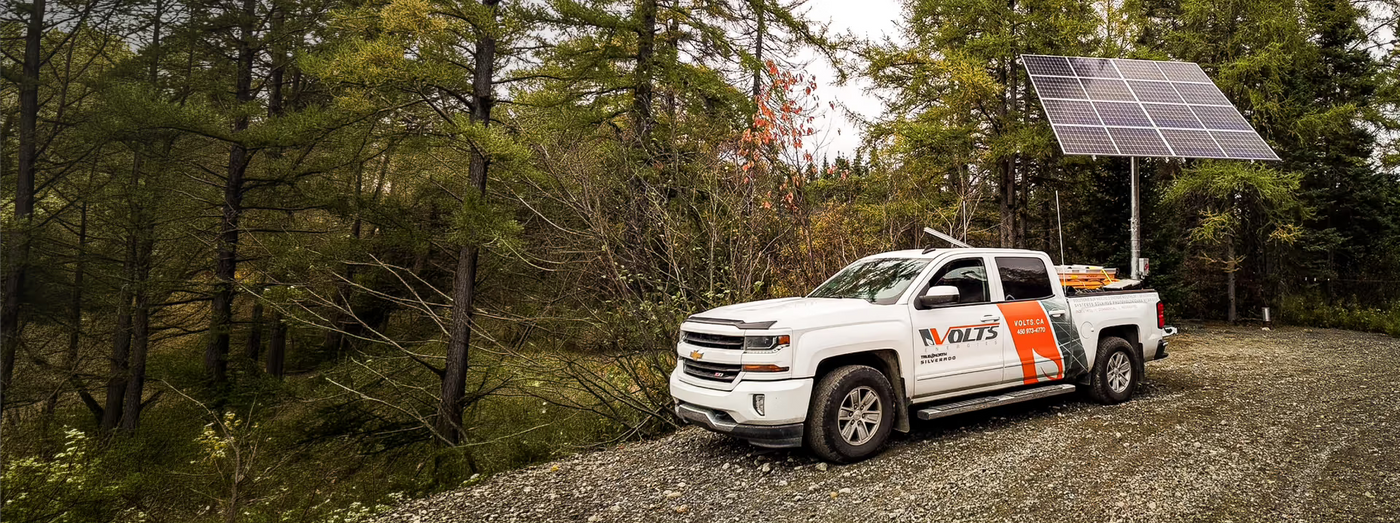 Volts Energies service truck beside a pole-mounted solar panel at a remote off-grid site in Canada