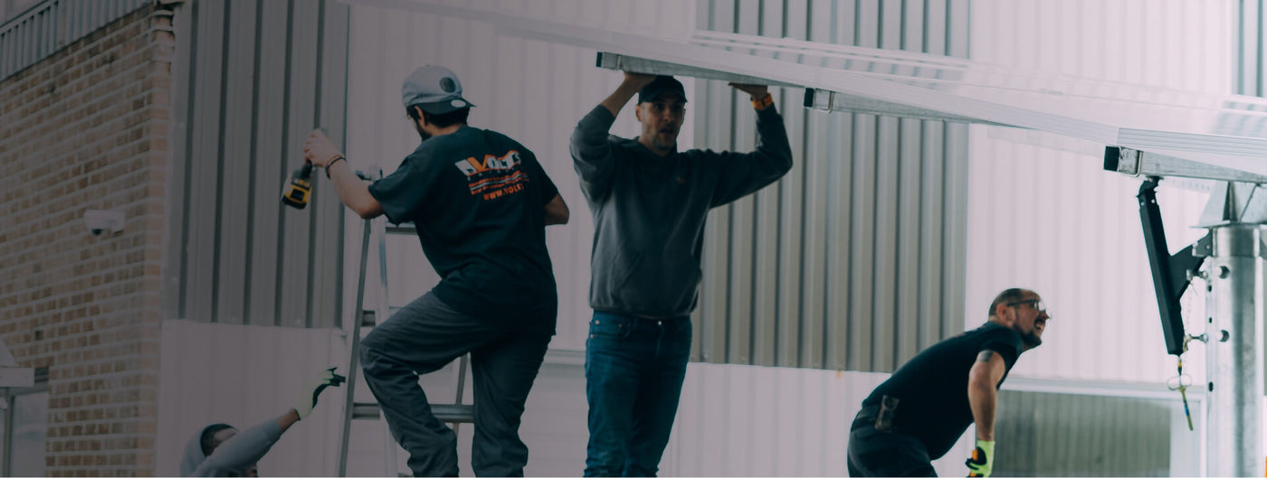 Volts Energies three-person team installing solar energy system on commercial building