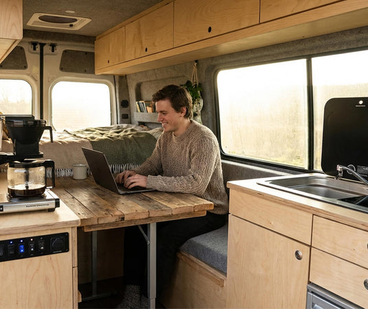 Interior of a custom Volts Energies camper van conversion showing a built-in desk and kitchen setup