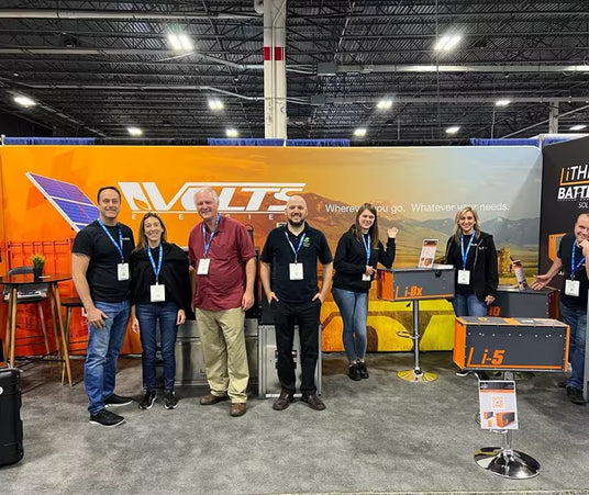 Volts Energies team at a trade show booth displaying portable lithium battery and solar energy products