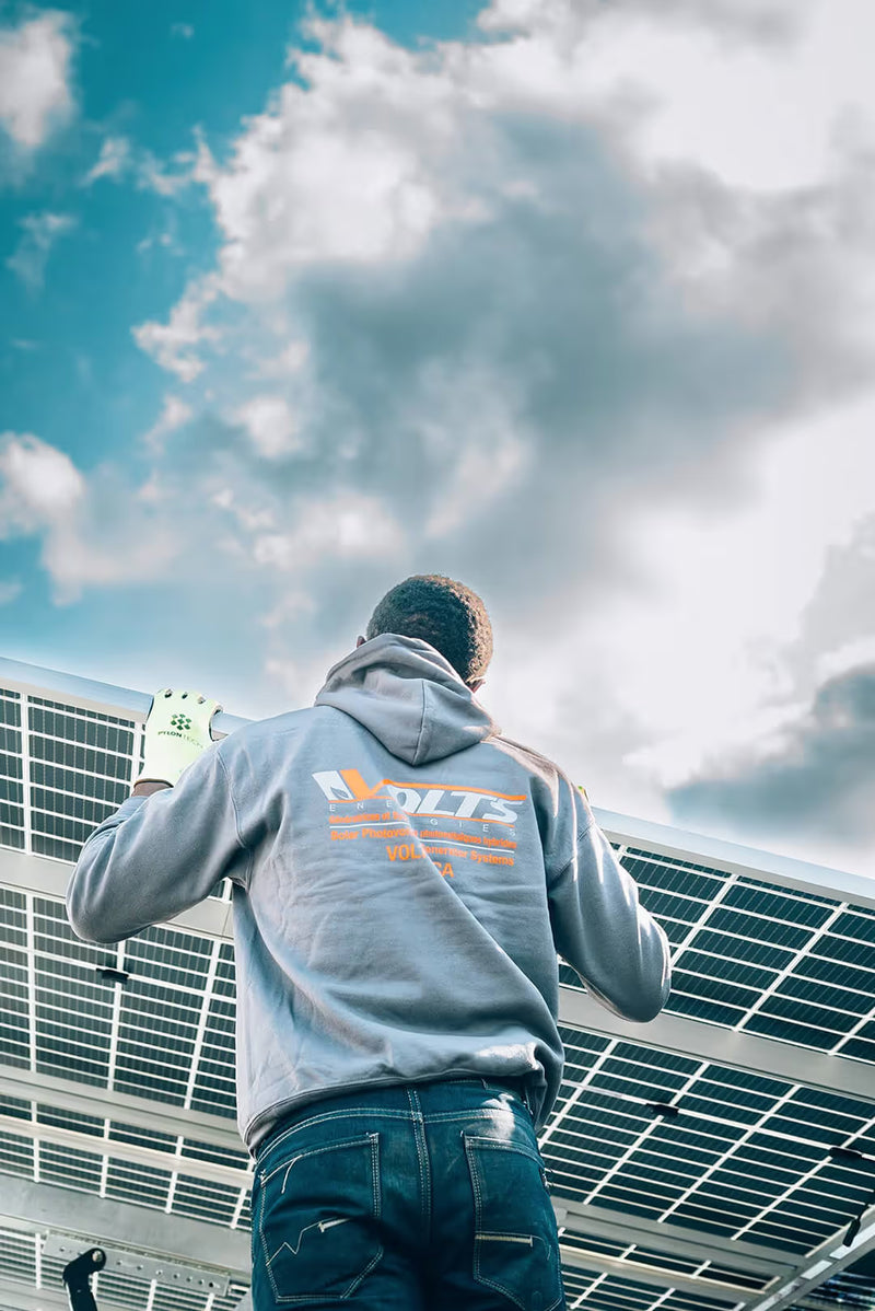 Volts Energies certified technician in branded jacket reviewing an electrical panel during a solar system installation